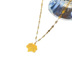 Minimalist gold maple leaf pendant necklace with design chain on a clean white background
