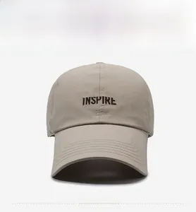 Detailed close-up of brown INSPIRE embroidery on beige quick-dry baseball cap