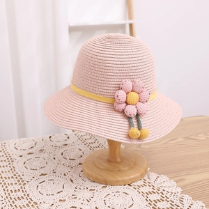Détail de chapeau en paille rose avec ruban jaune, fleur en tissu et support bois