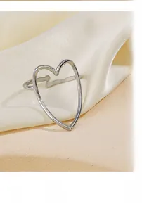 Macro shot of silver adjustable heart ring on beige silk showing delicate hollow design