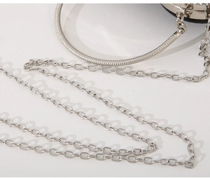 Detail of silver evening bag showing the metal top handle and sleek chain shoulder strap