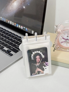 Close-up of a clear PVC photocard holder with 3-ring binder on a cozy desk setup