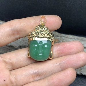 Detailed view of Buddha head pendant with green crystal stone and golden metal trim