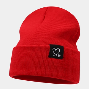 Détail du bonnet rouge en tricot avec une étiquette noire à motif cœur sur le rebord