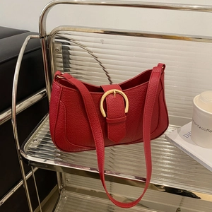 Detail of red lychee pattern leather shoulder bag with gold horseshoe buckle closure