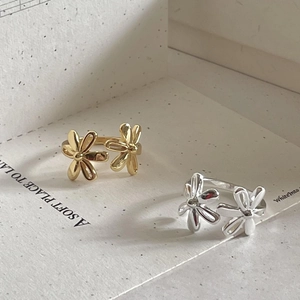 Detailed shot of gold and silver open daisy flower rings on elegant textured paper