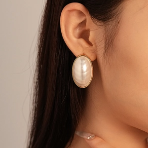 Close-up of model wearing vintage oval pearl earrings with gold-plated metal border
