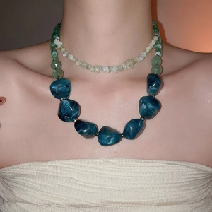 Detail view of double-layered necklace with green stone and blue marble resin pendant