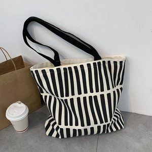 Detail of a black and white striped canvas tote bag with black fabric handles