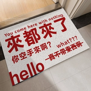 Gray non-slip door mat with funny red text placed at a home entrance on tiles