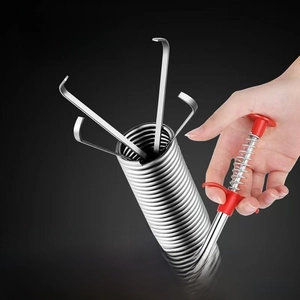 Close-up of flexible drain clog remover tool showing retractable four-claw grabber