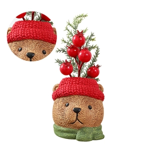 Macro detail of cartoon bear ornament with red knitted hat and green berry sprig
