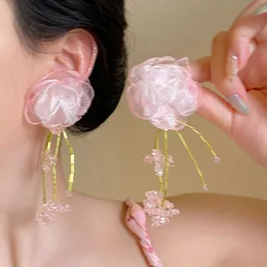 Detailed close-up of pink fabric flower earrings with elegant gold beaded tassels