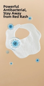 Detail of white cotton baby bib featuring absorbent gauze fabric and scalloped edges