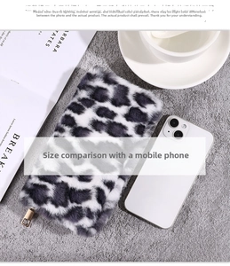 Close-up of leopard print plush wallet with gold zipper next to a smartphone