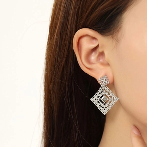 Detailed close-up of silver hollow geometric rhombus earrings with embedded zirconia