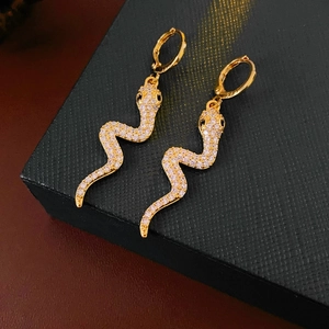 Detail of gold snake earrings with sparkling cubic zirconia on a black jewelry box