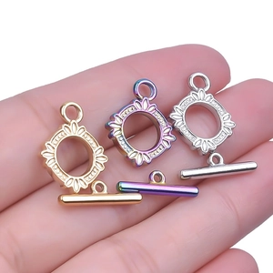 Dettaglio di chiusure OT in oro 18k, argento e arcobaleno tenute in mano per confronto