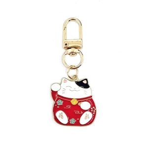 Detailed view of red and white Maneki Neko lucky cat keychain with gold hardware