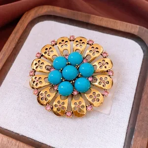 Vintage hollow flower brooch with pink diamonds and turquoise beads on a golden base
