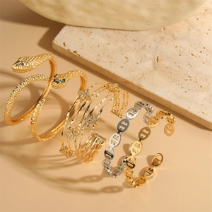 Detail of gold snake bangle with green stones and multi-layer clover flower bracelets