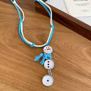 Détail d'un pendentif bonhomme de neige avec écharpe bleue sur plateau en bois