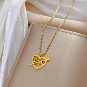 Détail du pendentif cœur doré avec gravure Love et flèche sur une chaîne vénitienne