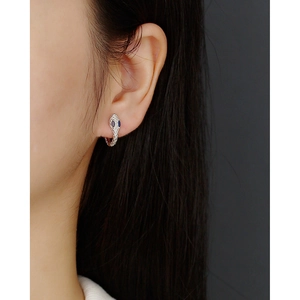 Close-up of S925 sterling silver snake earrings with blue gemstone eyes on model