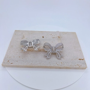 Boucles d'oreilles nœud argentées avec zircons présentées de face et de dos