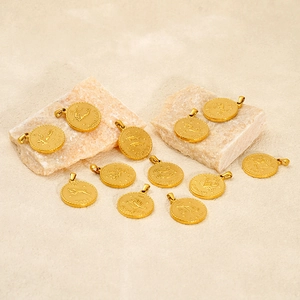 Minimalistische 18K Gold Sternzeichen Anhänger mit Sternbildern auf sandigen Steinen