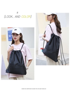 Detail view of black drawstring backpack showing bottom zipper pocket and shoulder straps