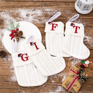 Macro detail of white knitted Christmas stockings with red embroidered G-I-F-T letters
