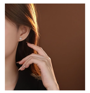Close-up of minimalist silver hollow rose earrings worn elegantly on a model ear