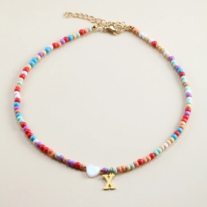 Detailed view of multi-color beaded necklace with a white heart and golden letter X pendant