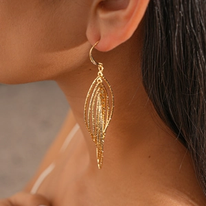 Close-up of golden multi-layer oval hook earrings with sparkling zircon on a model
