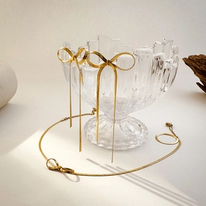 Detailed shot of gold bow tassel earrings and matching snake chain necklace set