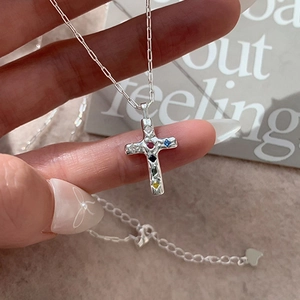 Dettaglio del ciondolo a croce in argento strutturato con pietre di zircone multicolore