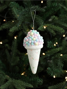 Close-up of glittery ice cream ornaments hanging on a Christmas tree with warm bokeh light