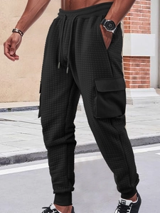 Close-up of men's black cargo joggers featuring waffle quilted texture and side pockets