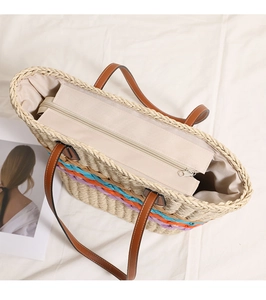 Top view of woven straw tote bag with rainbow stripes and brown leather zipper strap