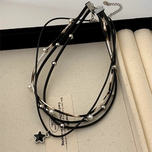Detail of layered black cord necklace with star pendant and pearl accents