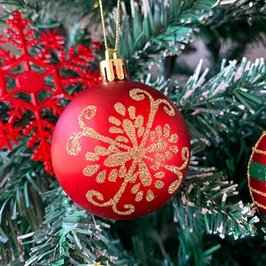 Dettaglio di palla di Natale rossa con fiocco di neve glitter oro su un albero