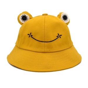 Close-up of a yellow frog bucket hat with 3D eyes and an embroidered smile on canvas