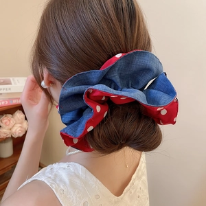 Detailed back view of a large denim blue and red polka dot fabric hair scrunchie on a bun