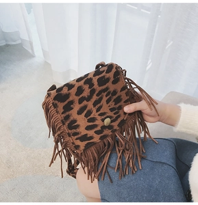 Detail of leopard print faux suede crossbody bag featuring long tassels and metal snap button