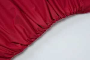 Detail of red ruched fabric with elastic gathers and smooth stretch material texture