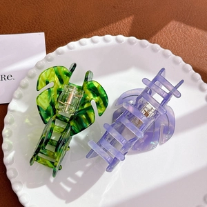 Leaf-shaped acetate hair claws in green and purple marble finish on ceramic tray