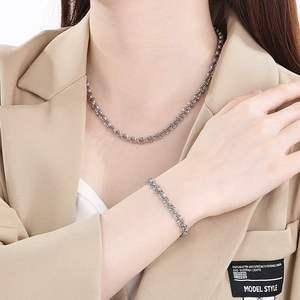 Detail of silver stainless steel chain necklace and bracelet set on a khaki suit