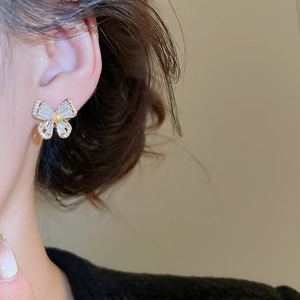 Detail of gold plated butterfly earrings with zircon inlay and elegant round pearl