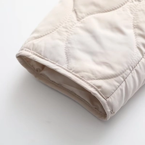 Detail of beige quilted jacket cuff showing premium stitching and nylon fabric texture